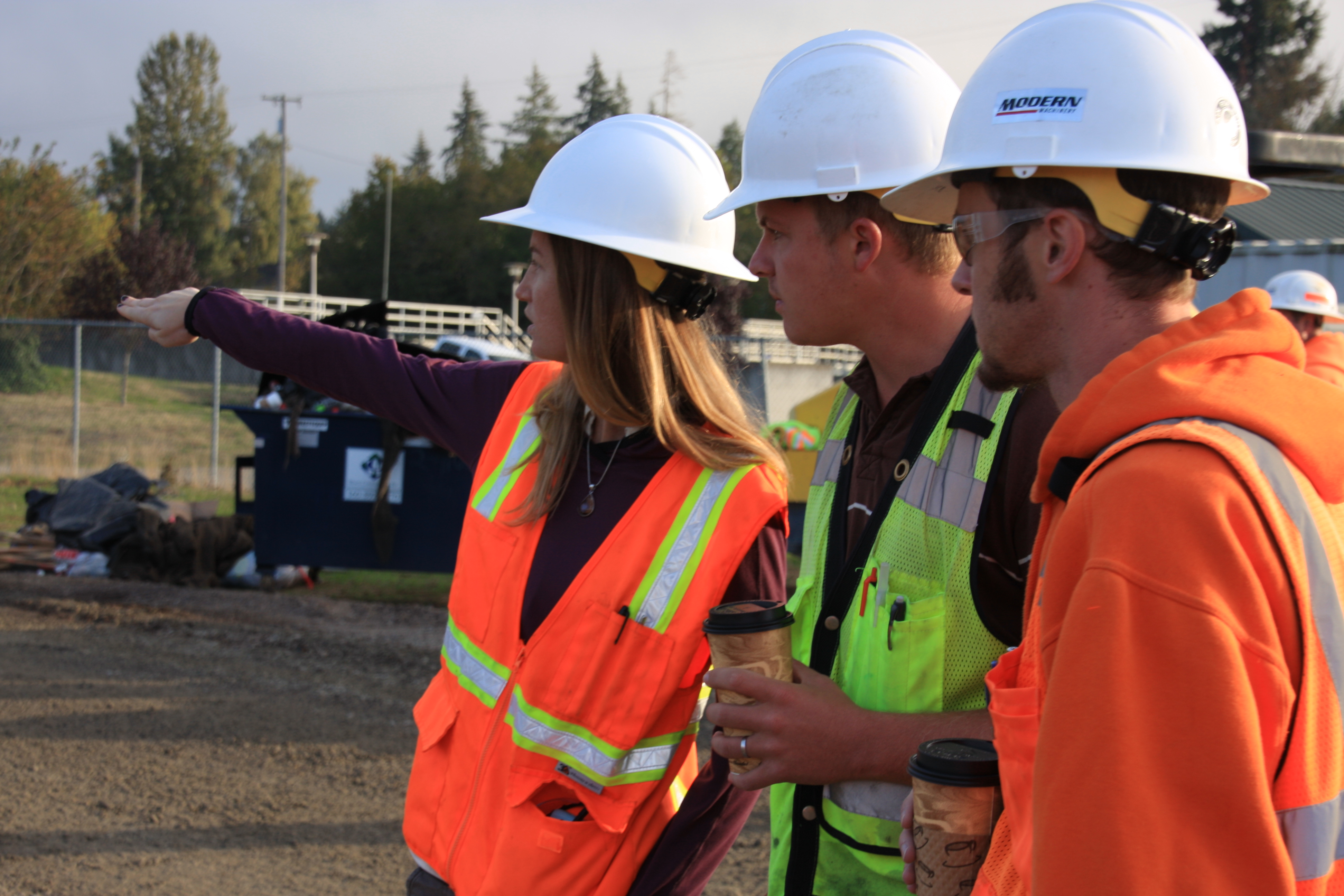 3 people in high visibility vests and hard hats on a construction site