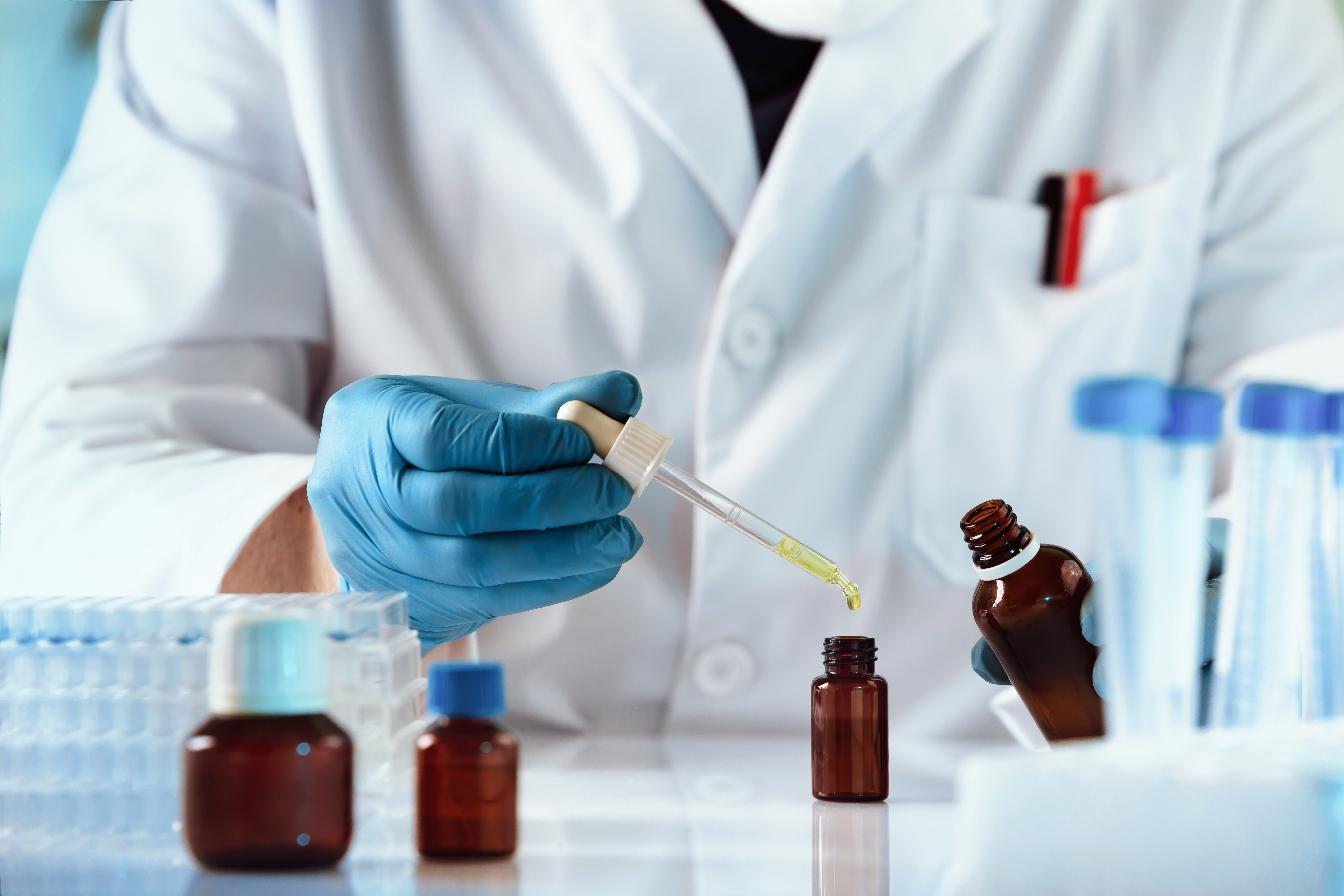 a chemist adding liquid to a bottle using an eyedropper