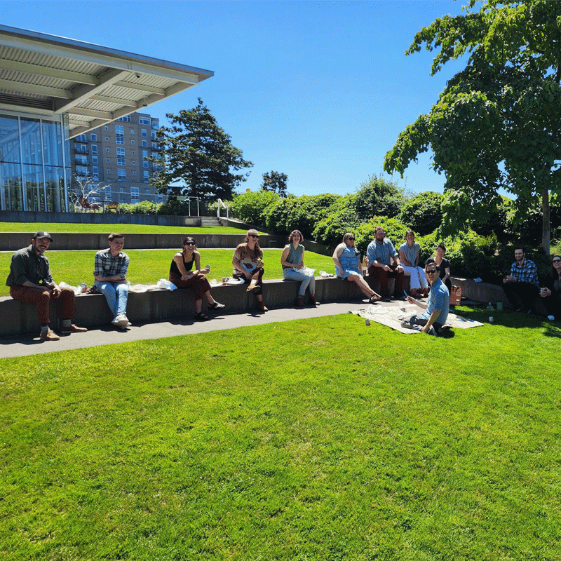 Group of people sitting on a lawn.