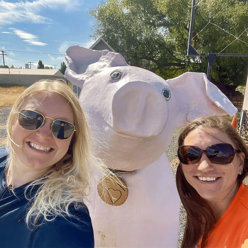 women next to fake pig