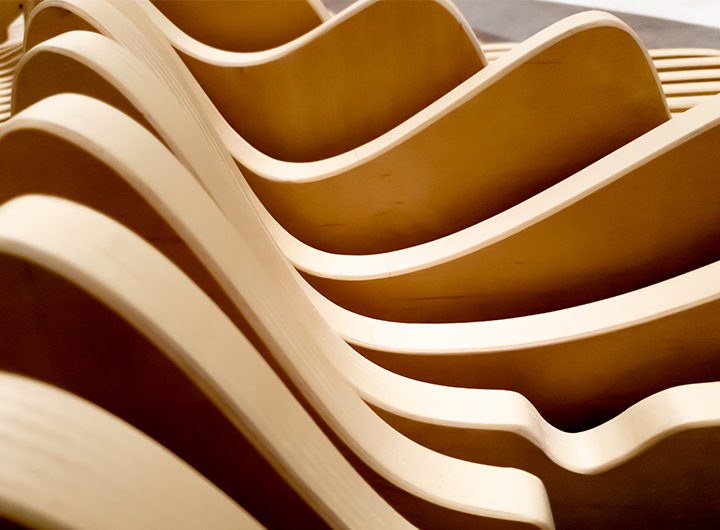 Curved laminated wood panels stacked in a repeating wave pattern.