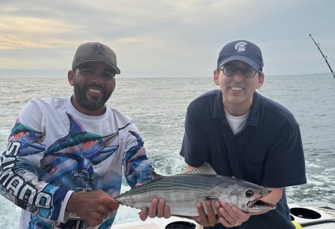 Bill Beadie on a boat holding a fish