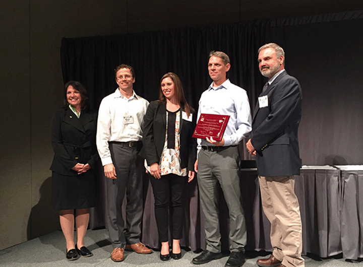 award recipients holding award plaque on stage