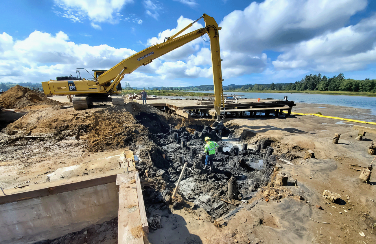 workers in safety gear digging next to an excavator